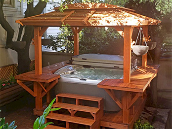This backyard spa is surrounded with redwood steps, roof and platforms.